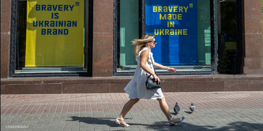 Uma mulher passa por grandes placas que diziam 'A bravura é uma marca ucraniana' em Kyiv. Oleksii Chumachenko/SOPA Images/LightRocket via Getty Images