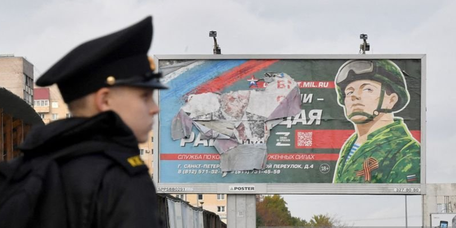 Um cadete militar fica perto de um outdoor promovendo o serviço militar em São Petersburgo em 5 de outubro de 2022 Olga Maltseva/AFP via Getty Images